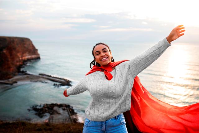 Mujer con una capa roja y el mar de fondo